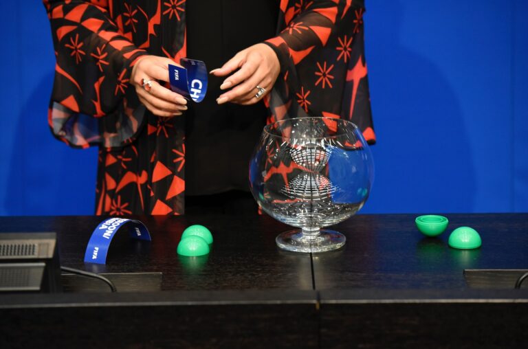 A guest draws the name of a team out of a pot during a FIFA draw. Photo courtesy of the official FIFA Facebook profile. World Cup 2026 draw featured image